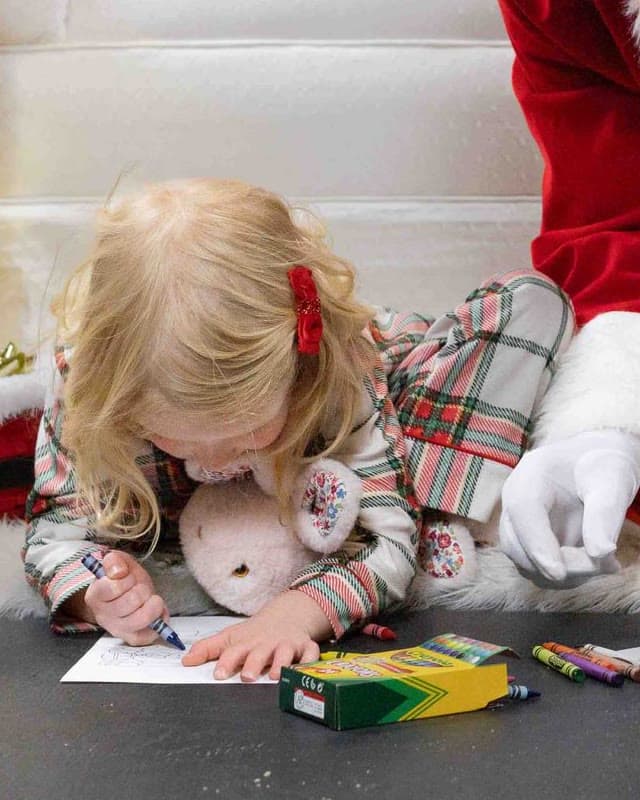 A little girl coloring a Christmas picture with crayons