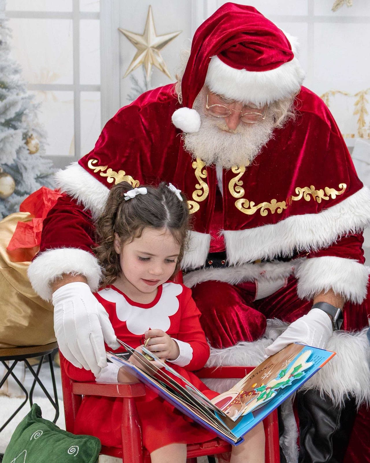Santa reading a Christmas pop-up book with a little girl