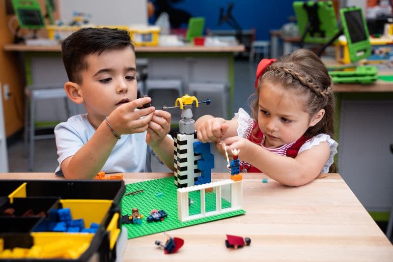 A boy and a girl fit a spinning piece onto the tower they are building