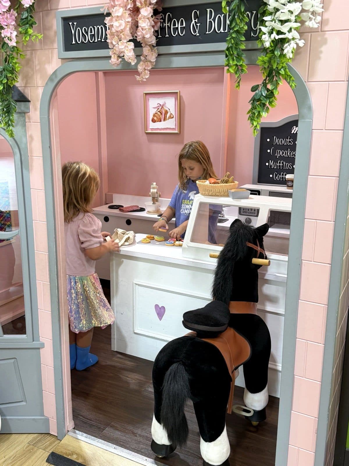 Two children playing shop in the bakery playhouse