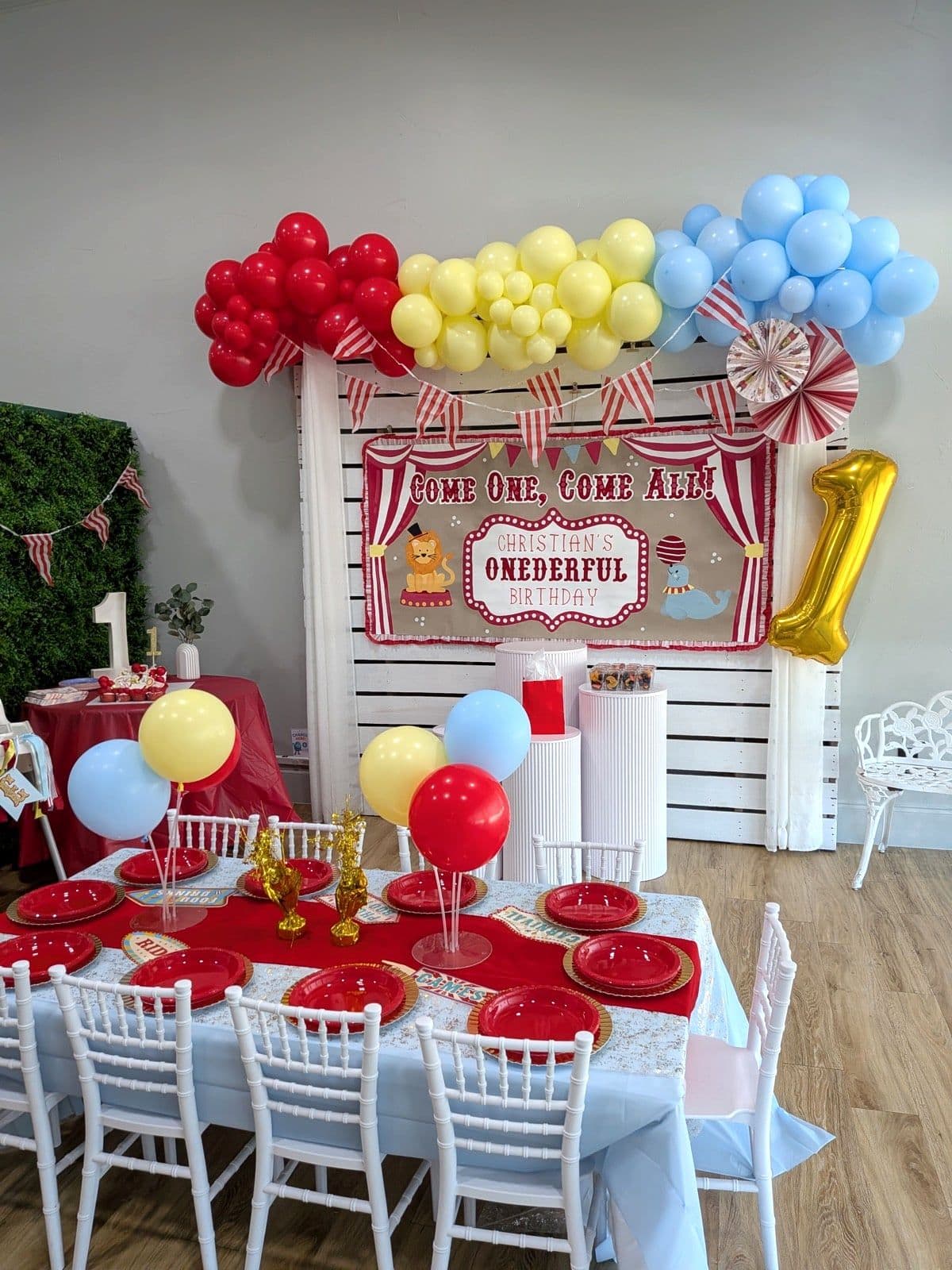 Circus birthday party setup with a striped backdrop and balloon garland