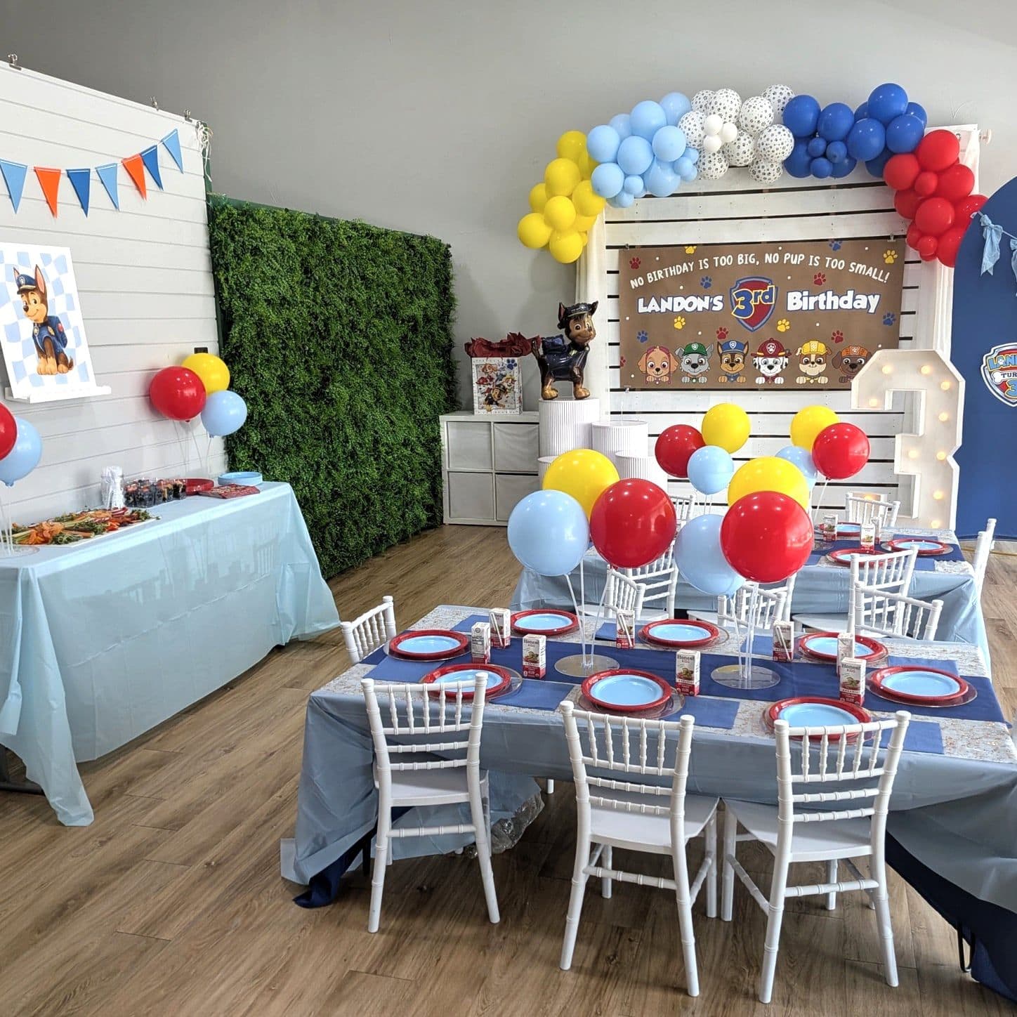Rescue pup birthday party setup with a red, blue and yellow balloon arch