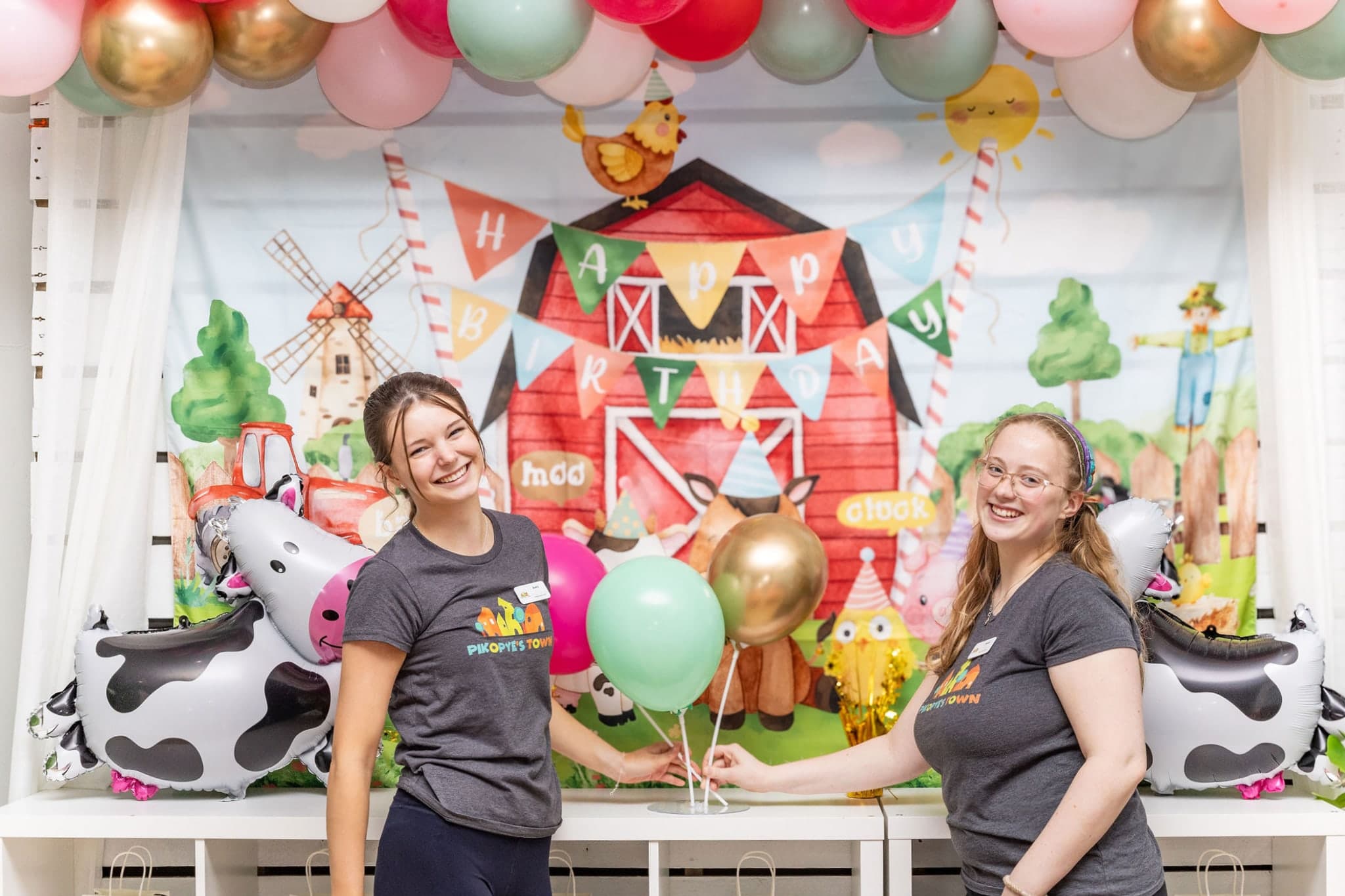 Party hosts smiling in front of backdrop