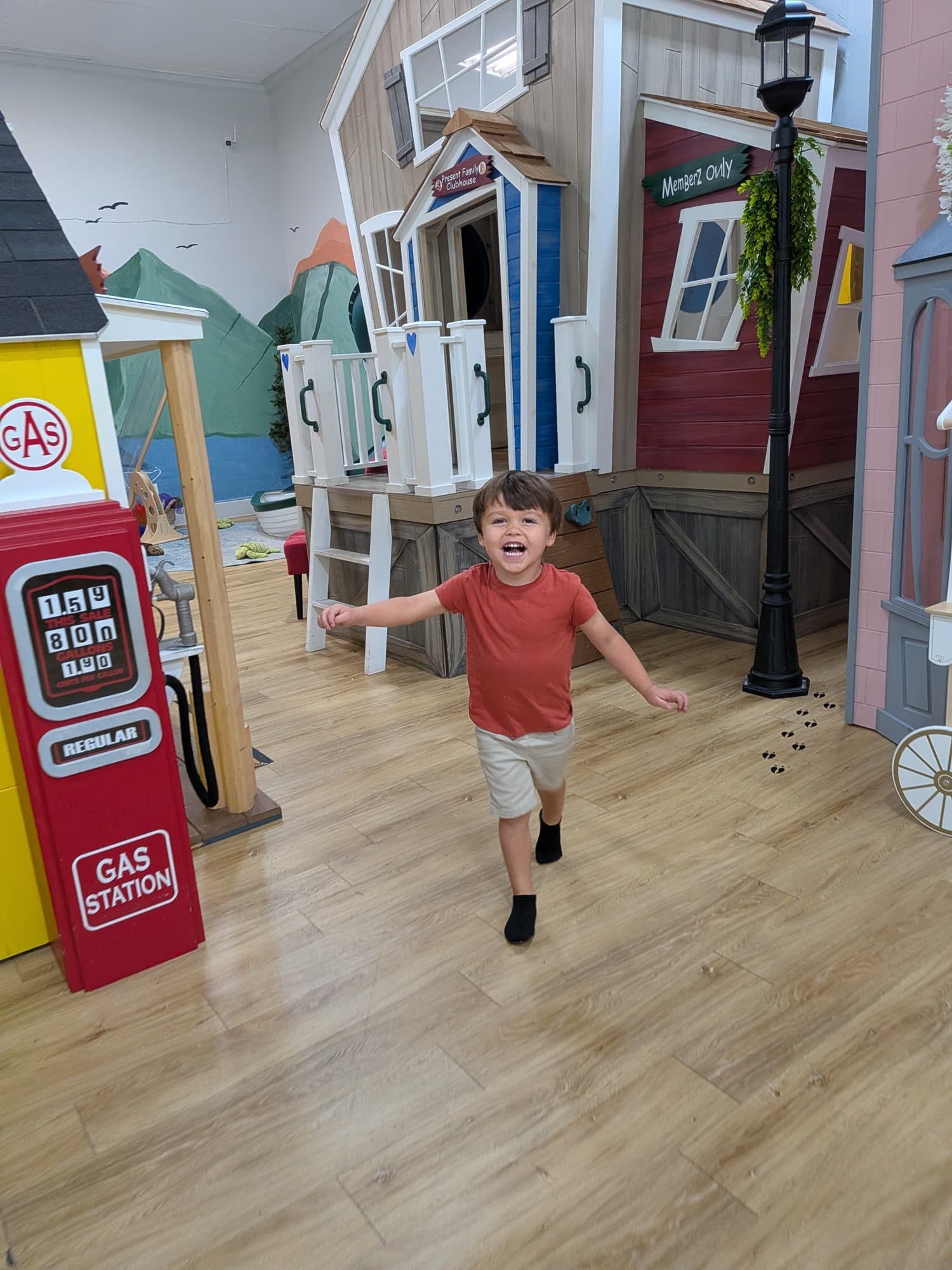 A laughing child runs down the street of the play town at Pikopye's Town